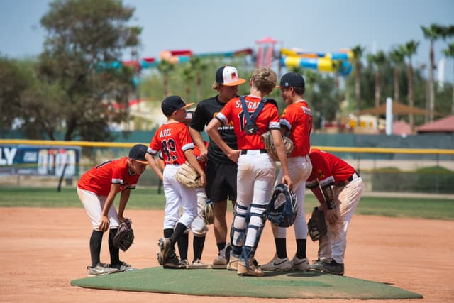 AZ643 players gathered with their coach on the pitcher's mound during a game