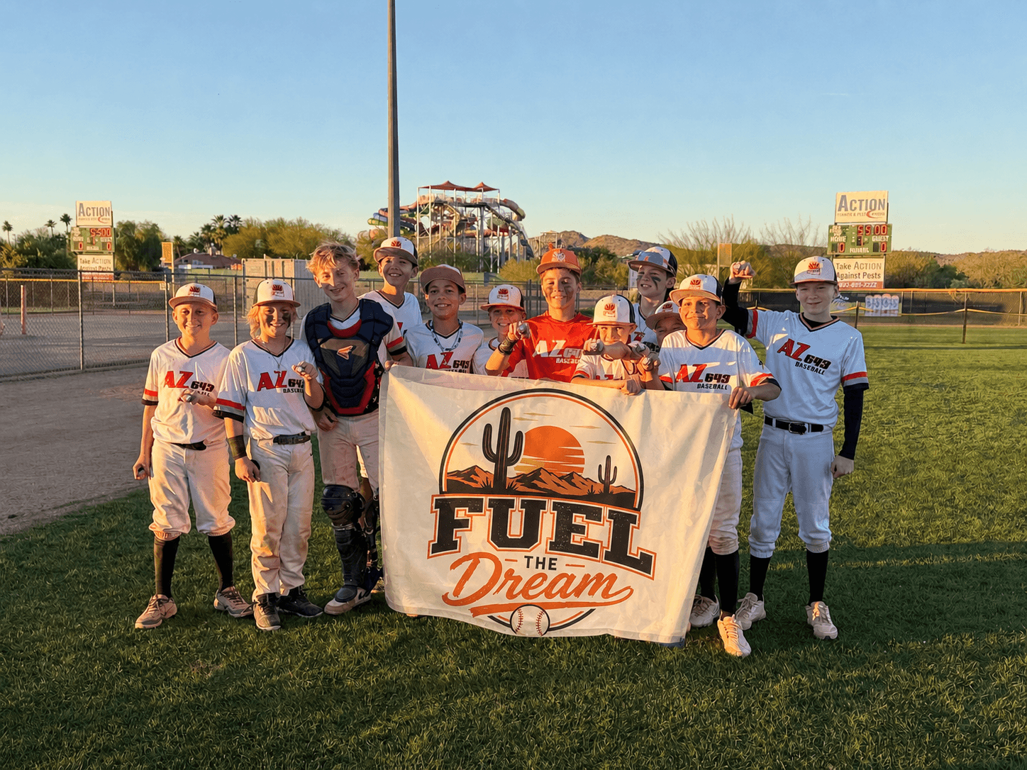 The AZ643 12U team on the field at sunset, holding a Fuel the Dream banner